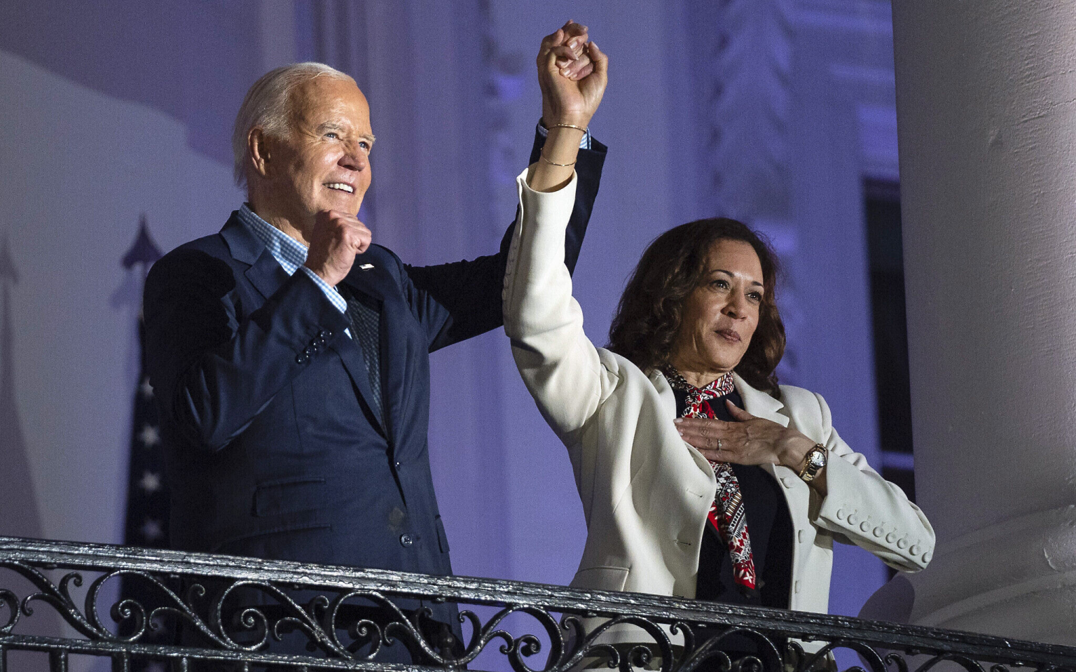 US President Joe Biden raises the hand of Vice President Kamala Harris after viewing the Independence Day fireworks display over the National Mall from the balcony of the White House, July 4, 2024, in Washington. (Credit: Associated Press / Evan Vucci)