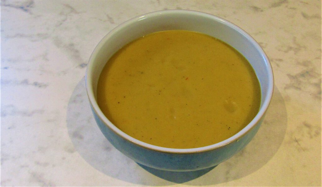 A bowl of brown butter pumpkin soup topped with creme fraiche and toasted pumpkin seeds