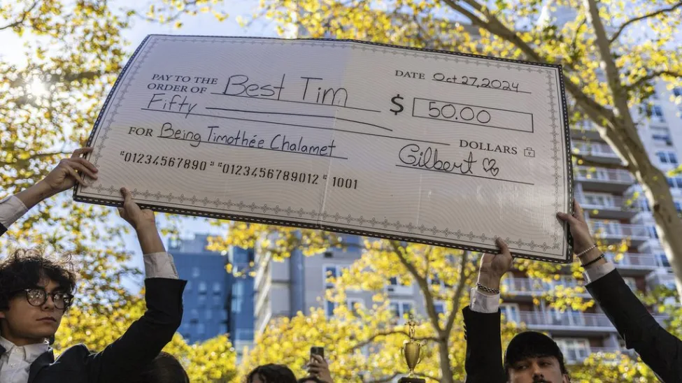 Timothée Chalamet Crashes Look-Alike Contest in New York City 3 A giant cheque for the prize money is held aloft at the Timothee Chalamet lookalike contest near Washington Square Park, Sunday, Oct. 27, 2024, in New York. (Image Credit: AP / Stefan Jeremiah)