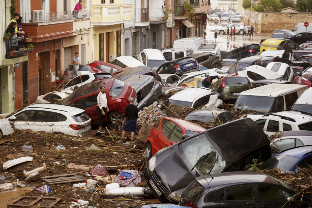 Spain Floods Latest: Flash Flooding In Valencia Claims 95 Lives, With Dozens Still Missing 2 Residents look at cars piled up after being swept away by flooding Valencia, Spain. (Image Credit: Alberto Saiz / AP)