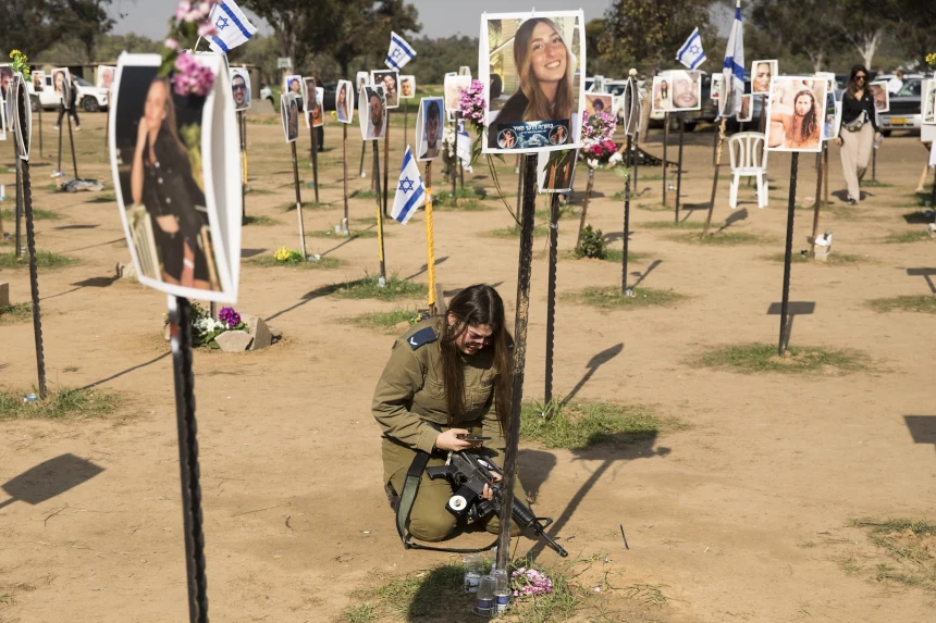 An Israeli soldier beneath photos of civilians who died at the Nova music festival site in Re'im, Israel after the 7 October attack. (Credit:Amir Levy / Getty Images)
