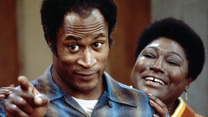 John Amos, Iconic Star of ‘Good Times’ and ‘Roots,’ Passes Away at 84 2 John Amos (left) and Esther Rolle (right) on "Good Times." He was 84 years old as the time of his death. (Credit: Getty Images)