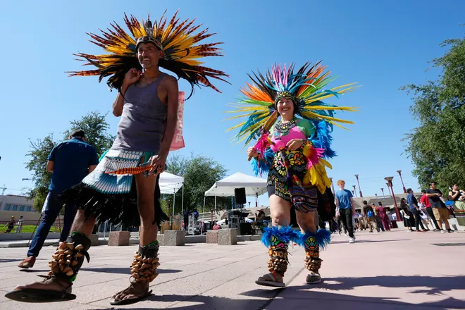 What Is Columbus Day Holiday 2024: History and Controversial Holiday 3 People wearing traditional Aztec dance clothing walk through an Indigenous Peoples' Day festival, instead of Columbus Day. (Image Credit: Ross D. Franklin)