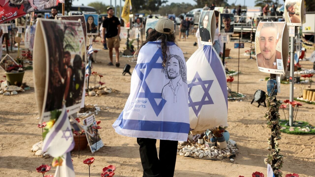 Israelis wrapped in flags visit the site of the October 7 Nova music festival massacre, on October 7, 2024. (Image Credit: AP/ Ohad Zwigenberg)