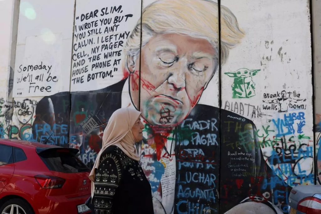 Hamas calls for war end immediate after President Donald Trump was re-elected.
Mural that depicts President Donald Trump, in Bethlehem is a city in the Israeli-occupied West Bank of the State of Palestine, located about ten kilometres (six miles) south of Jerusalem. (Image Credit: Hazem Bader / AP)