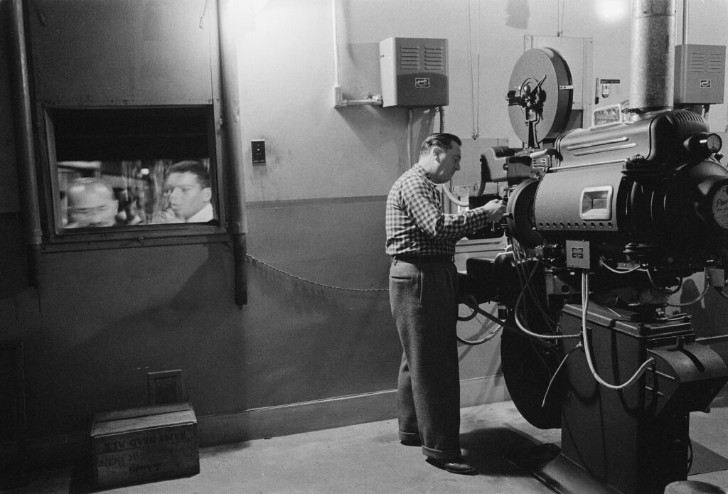 Man working with a projector in a movie theater