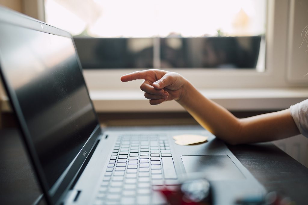 Child interacts with laptop screen while seated at a desk
