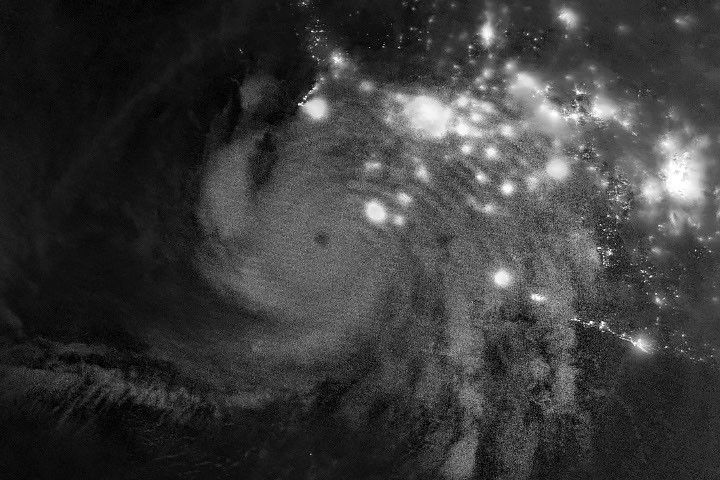 Gravity waves in the upper atmosphere appear as a semicircle of ripples in a nighttime, grayscale satellite image. Hurricane clouds and city lights in Mexico are also visible.