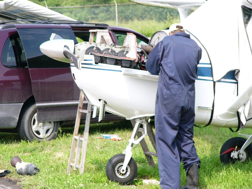 Commercial airplane on tarmac with maintenance crew working on landing gear