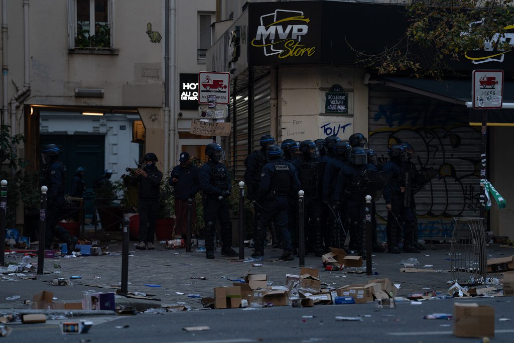 Police officers in riot gear standing near barricades during France curfews in Paris
