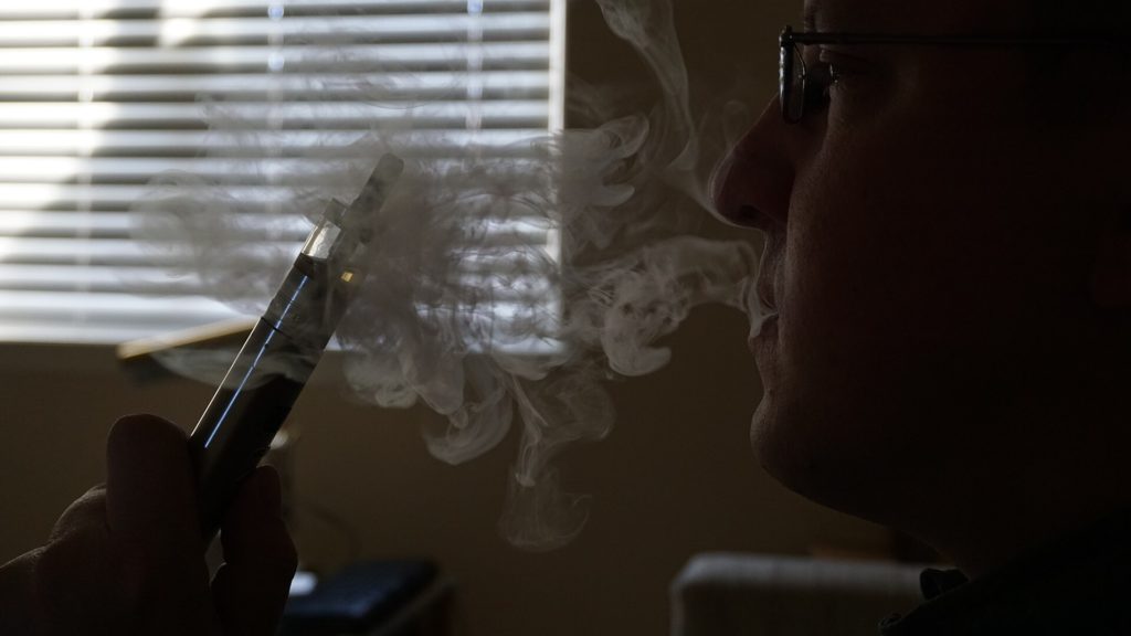 Close up of e-cigarette device and liquid bottles on a table representing vaping among never-smokers
