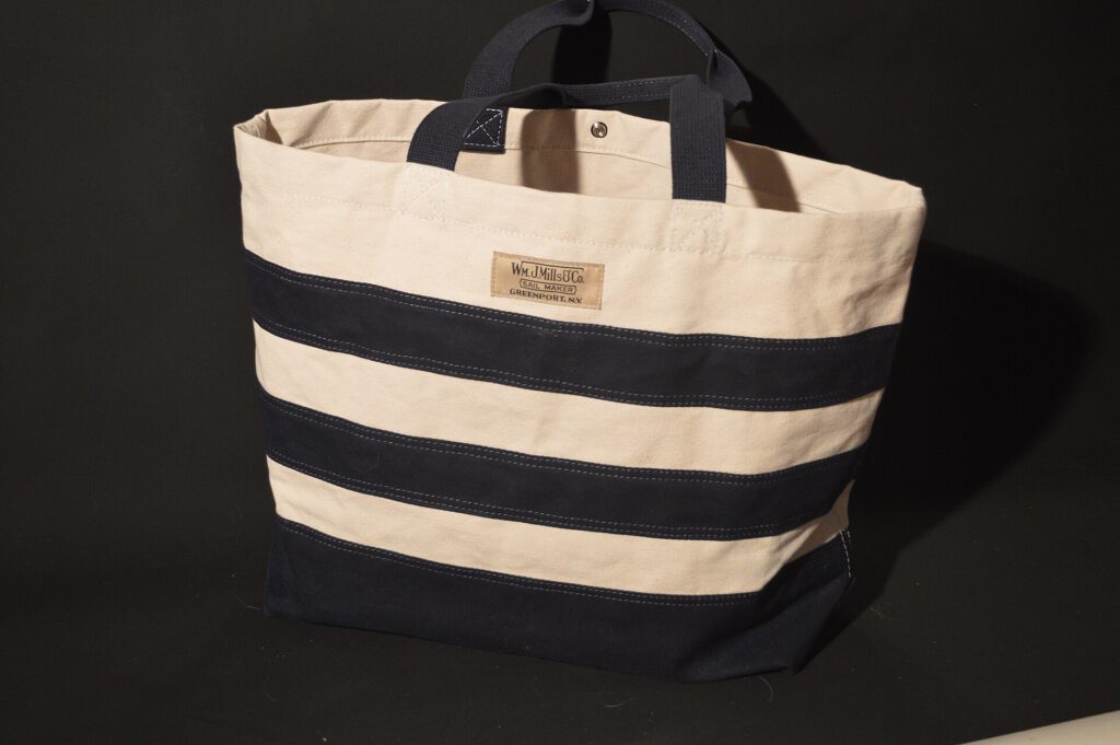 A white canvas tote bag with leather handles on a wooden table